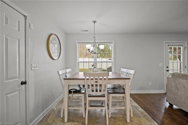 dining room featuring dark hardwood / wood-style flooring, an inviting chandelier, and plenty of natural light