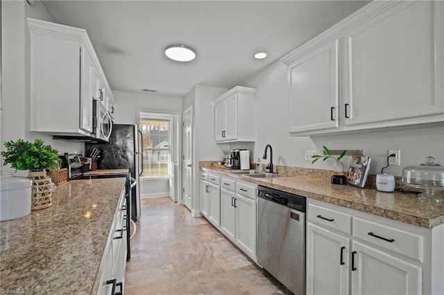 kitchen with light stone countertops, stainless steel appliances, white cabinetry, and sink