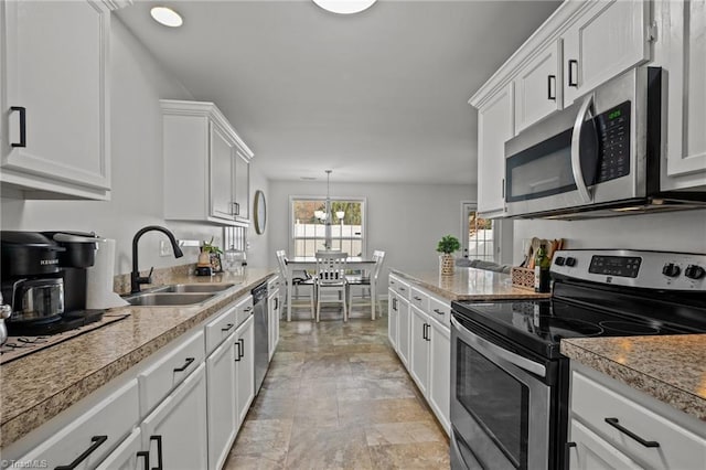 kitchen featuring white cabinets, sink, decorative light fixtures, a notable chandelier, and stainless steel appliances