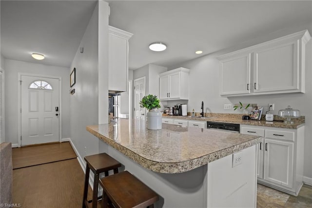 kitchen with white cabinets, dishwashing machine, a kitchen bar, and kitchen peninsula