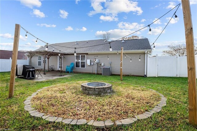 rear view of property featuring a fire pit, cooling unit, a patio area, and a lawn