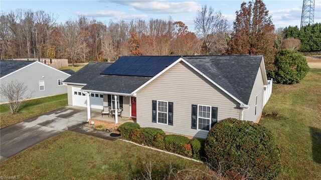 view of front of house with a porch, solar panels, and a front lawn