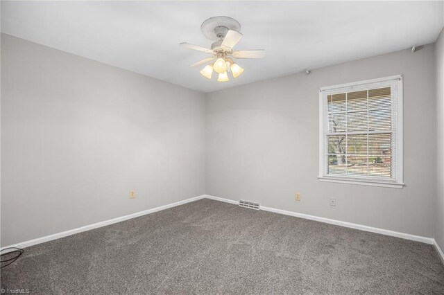 unfurnished room featuring a ceiling fan, dark carpet, visible vents, and baseboards