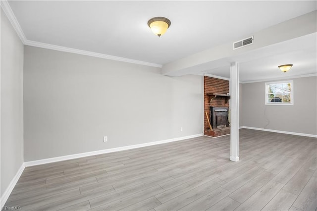 unfurnished living room featuring visible vents, baseboards, light wood-style floors, ornamental molding, and a brick fireplace