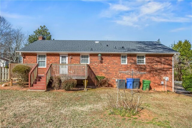 rear view of house with brick siding, a chimney, a lawn, cooling unit, and a wooden deck