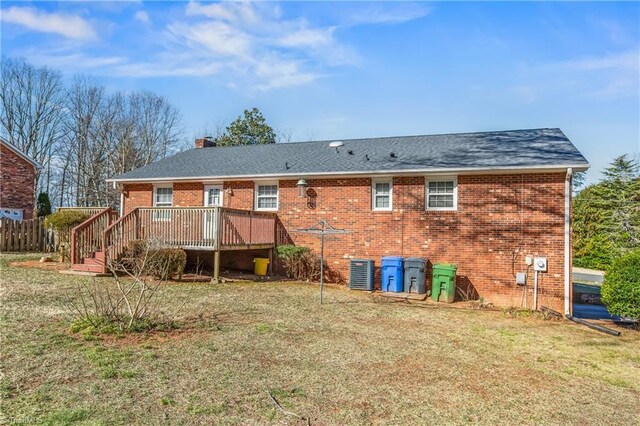 rear view of house featuring central air condition unit, a yard, a deck, and brick siding