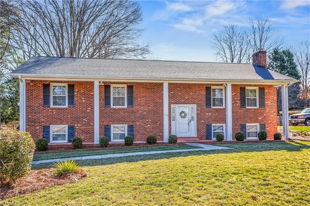 bi-level home featuring a front yard, brick siding, and a chimney