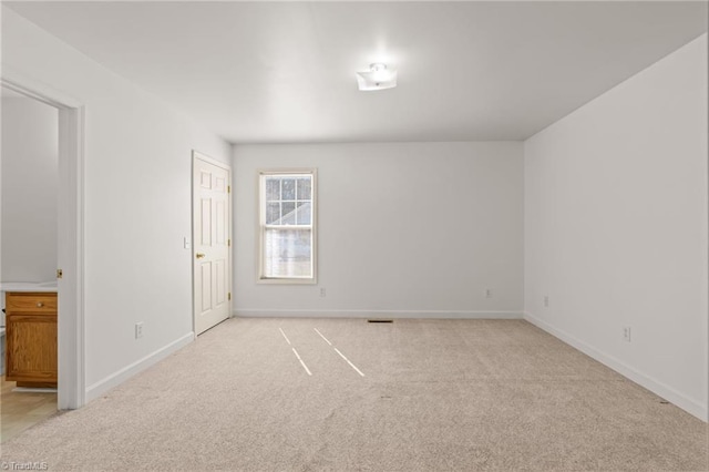 empty room featuring light colored carpet, visible vents, and baseboards