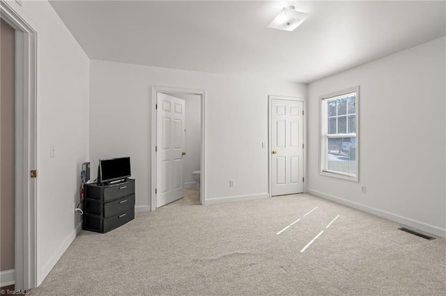 unfurnished bedroom with light carpet, baseboards, visible vents, and connected bathroom