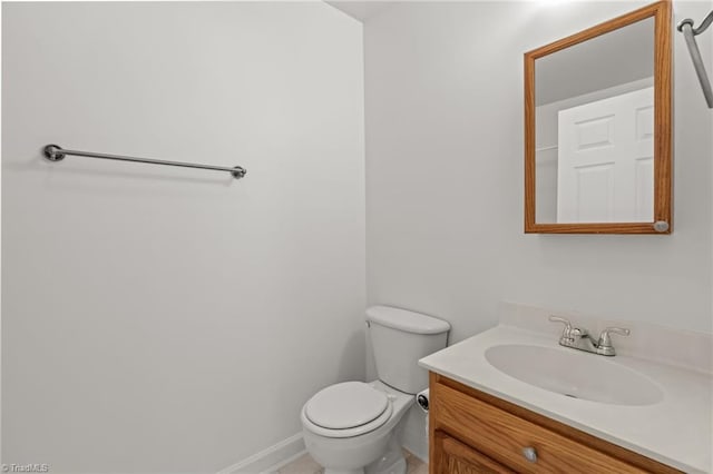 half bathroom with toilet, baseboards, and vanity