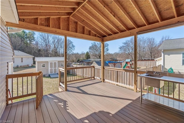 wooden deck with an outbuilding, fence, a yard, a shed, and a playground