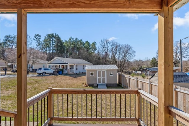 wooden deck featuring a lawn, a fenced backyard, a residential view, a storage unit, and an outdoor structure