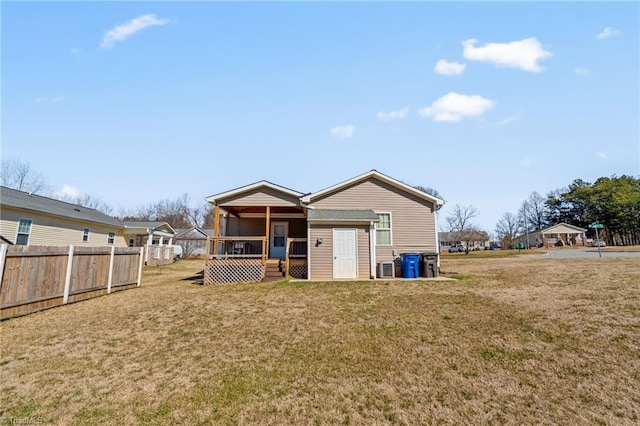 rear view of house with a lawn and fence