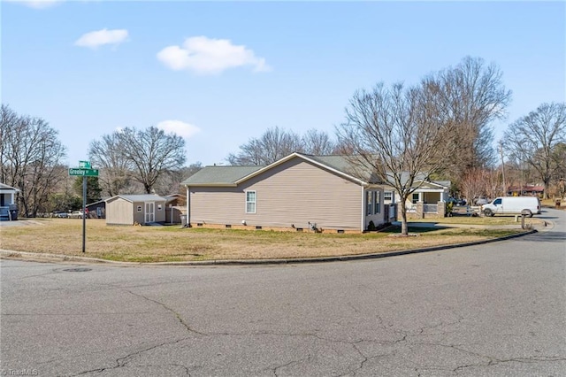 view of home's exterior featuring a residential view, crawl space, a yard, and a shed