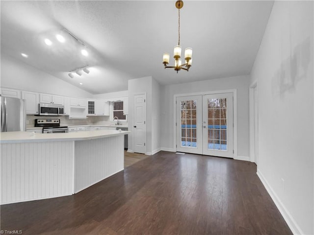 kitchen featuring dark wood-style flooring, stainless steel appliances, light countertops, vaulted ceiling, and french doors