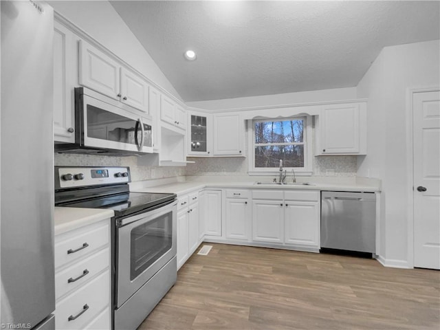 kitchen featuring a sink, lofted ceiling, appliances with stainless steel finishes, and white cabinets