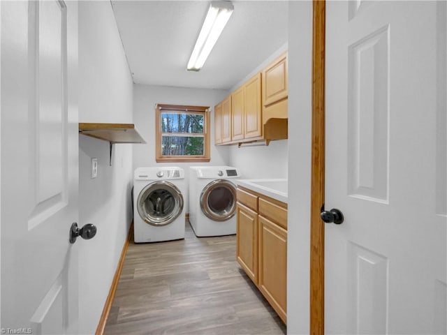 washroom featuring light wood-type flooring, cabinet space, baseboards, and washing machine and dryer