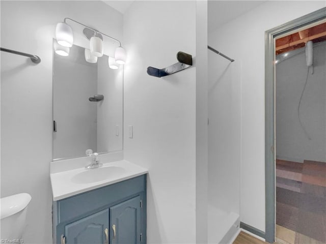 bathroom with toilet, vanity, and walk in shower