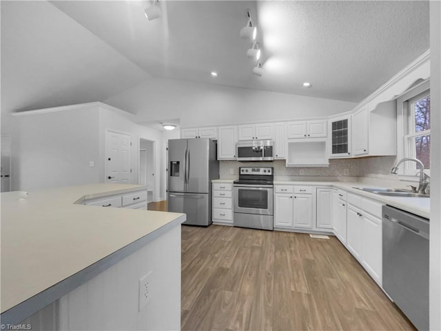 kitchen featuring vaulted ceiling, light wood-style floors, appliances with stainless steel finishes, and a sink