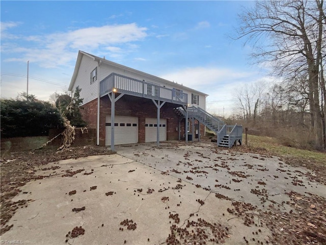 view of front facade featuring a wooden deck, an attached garage, stairs, concrete driveway, and brick siding