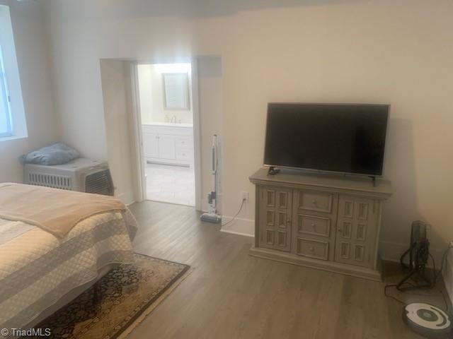 bedroom with hardwood / wood-style flooring, ensuite bath, and sink