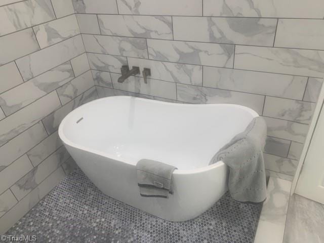 bathroom with a washtub and tile walls