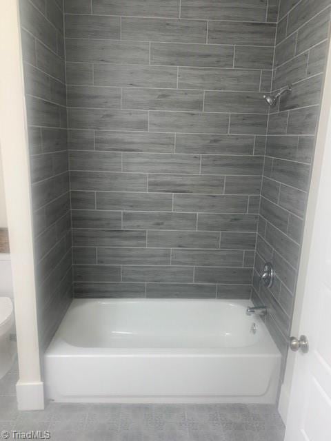 bathroom featuring toilet and tiled shower / bath