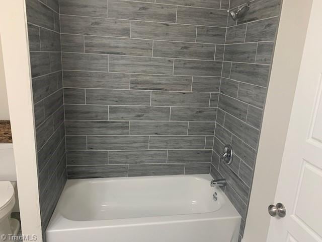 bathroom with tiled shower / bath combo and toilet