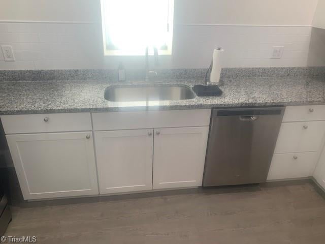 kitchen featuring stainless steel dishwasher, decorative backsplash, white cabinets, and light stone counters