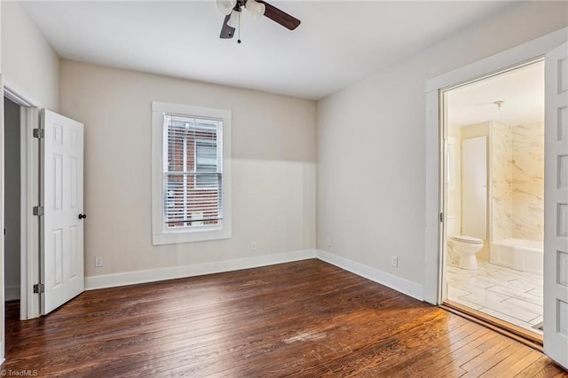 unfurnished bedroom with ceiling fan, ensuite bathroom, and dark hardwood / wood-style floors