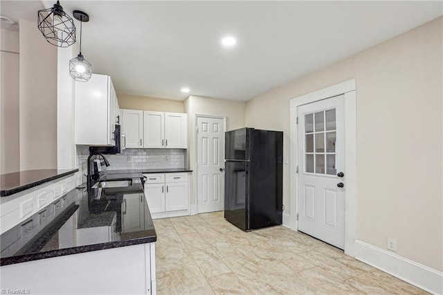 kitchen featuring white cabinetry, hanging light fixtures, tasteful backsplash, and black fridge