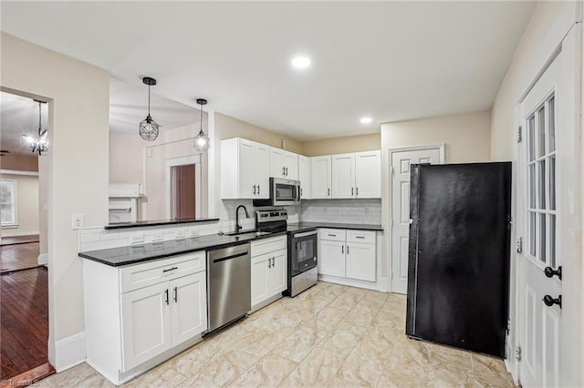 kitchen featuring sink, appliances with stainless steel finishes, hanging light fixtures, backsplash, and white cabinets