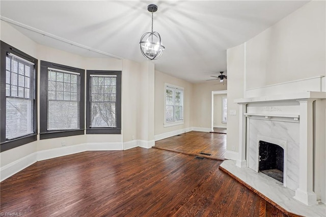 unfurnished living room featuring ceiling fan with notable chandelier, hardwood / wood-style floors, and a high end fireplace