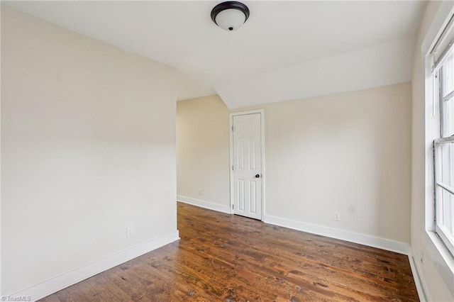 unfurnished room featuring lofted ceiling and dark hardwood / wood-style flooring