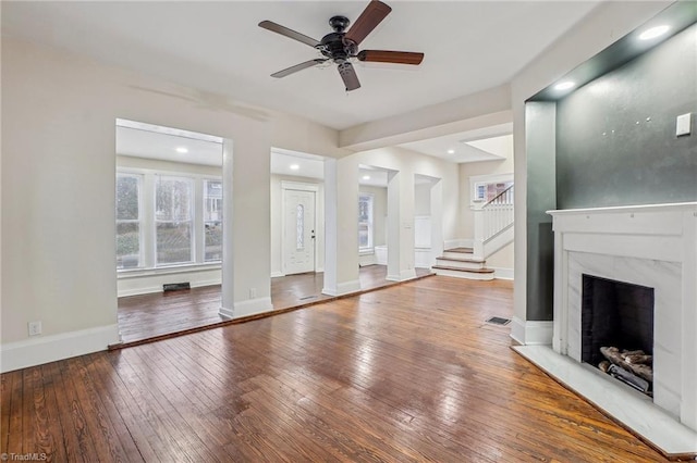 unfurnished living room with wood-type flooring, ceiling fan, and a fireplace