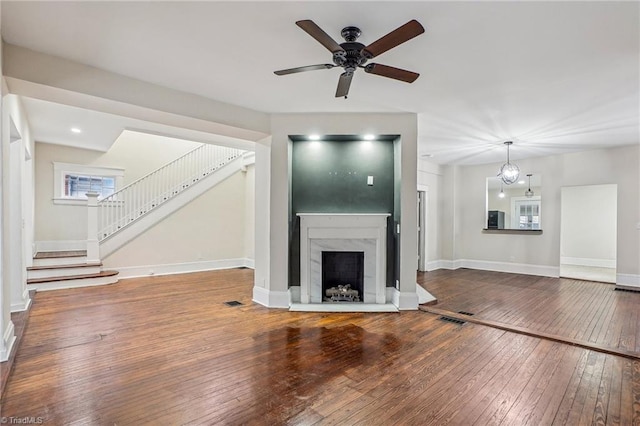 unfurnished living room featuring hardwood / wood-style flooring, a premium fireplace, and ceiling fan