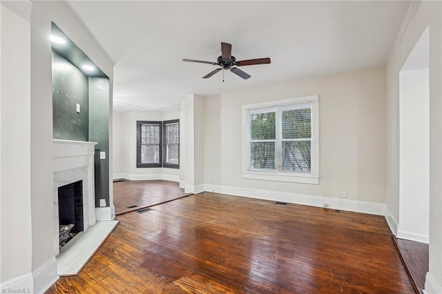 unfurnished living room featuring ceiling fan, a premium fireplace, and hardwood / wood-style floors