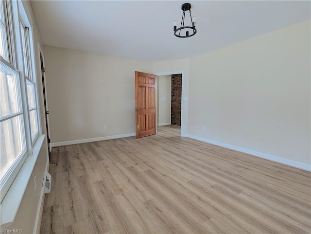 spare room featuring a notable chandelier and light wood-type flooring