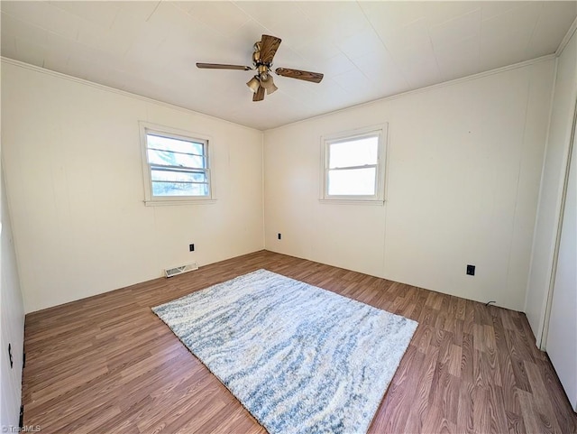 spare room with hardwood / wood-style floors, a wealth of natural light, and crown molding