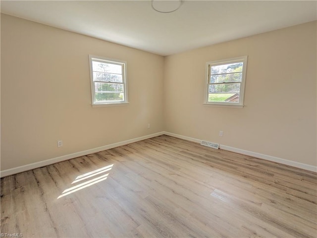 spare room with plenty of natural light and light hardwood / wood-style floors