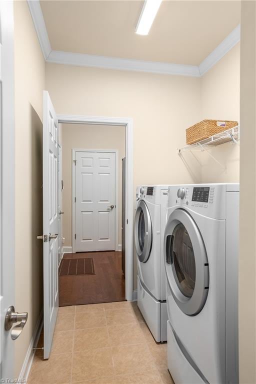 laundry room with ornamental molding, washer and dryer, light tile patterned floors, baseboards, and laundry area