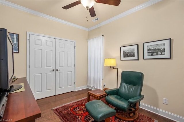 living area featuring visible vents, baseboards, wood finished floors, and crown molding