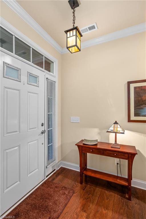 entrance foyer with visible vents, wood finished floors, baseboards, and ornamental molding