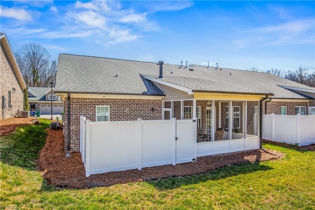 back of property featuring brick siding, central air condition unit, a yard, and a sunroom