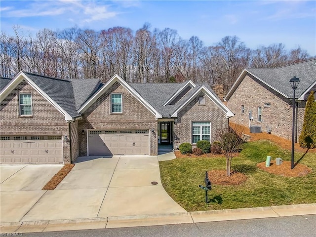 traditional-style house with brick siding, a front lawn, concrete driveway, central AC, and a garage