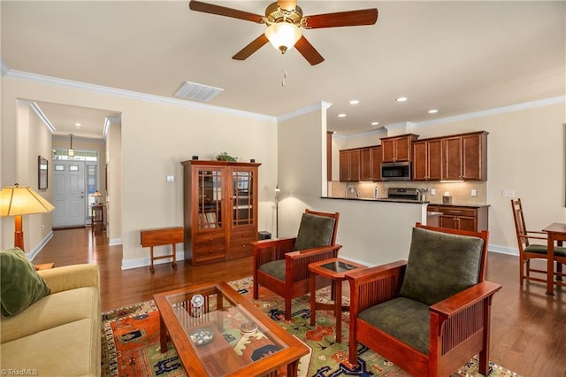 living area featuring dark wood finished floors, crown molding, baseboards, and visible vents