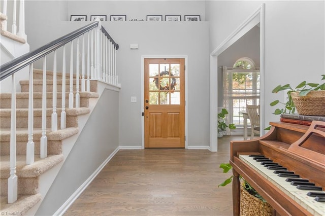 foyer entrance featuring light hardwood / wood-style flooring and a towering ceiling