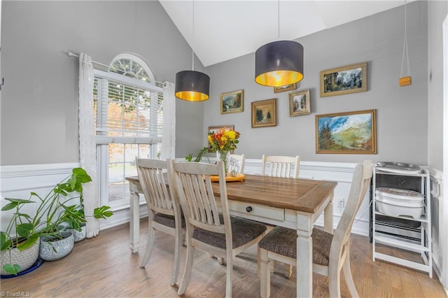 dining area featuring high vaulted ceiling and light hardwood / wood-style floors