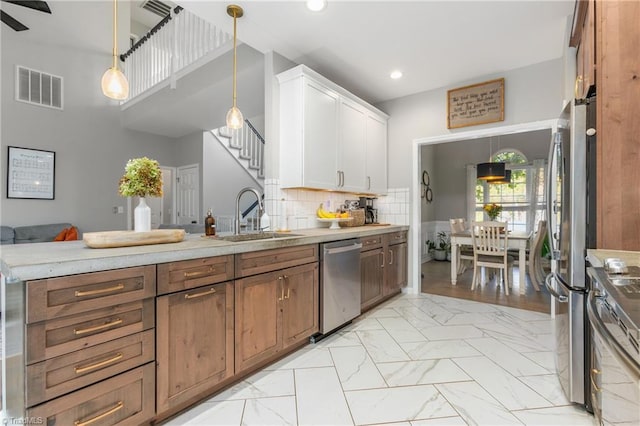 kitchen featuring white cabinets, sink, decorative backsplash, decorative light fixtures, and stainless steel appliances