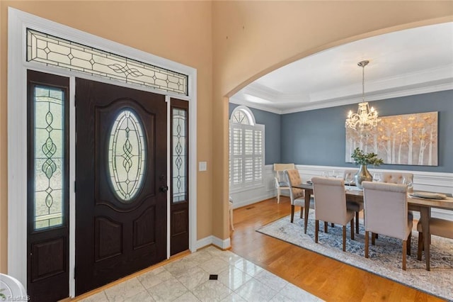 142 Covington Pl, Lewisville, NC 27023 - entrance foyer with arched walkways, ornamental molding, a chandelier, and a wainscoted wall